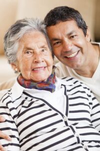 Adult daughter hugging her elderly mother smiling