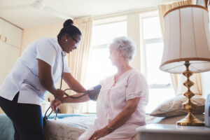 nurse taking blood pressure of patient at home 