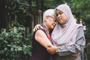Older woman and adult daughter holding each other solemnl