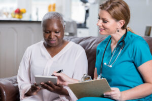african-american woman sits with hospice nurse talking about care services