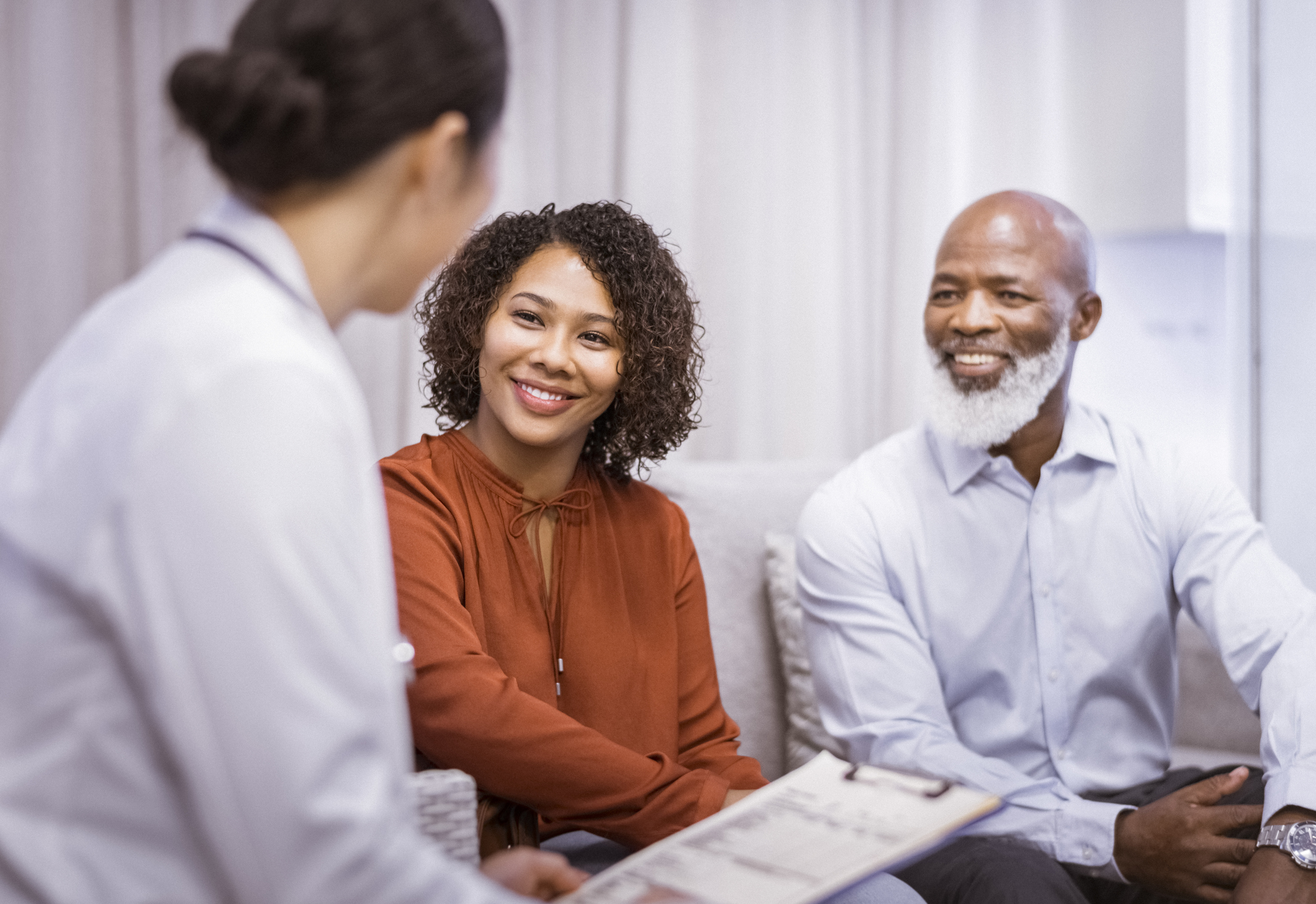 Smiling father and daughter with female doctor
