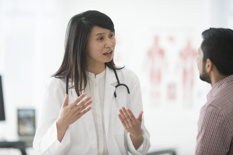 adult female doctor talking to young male patient