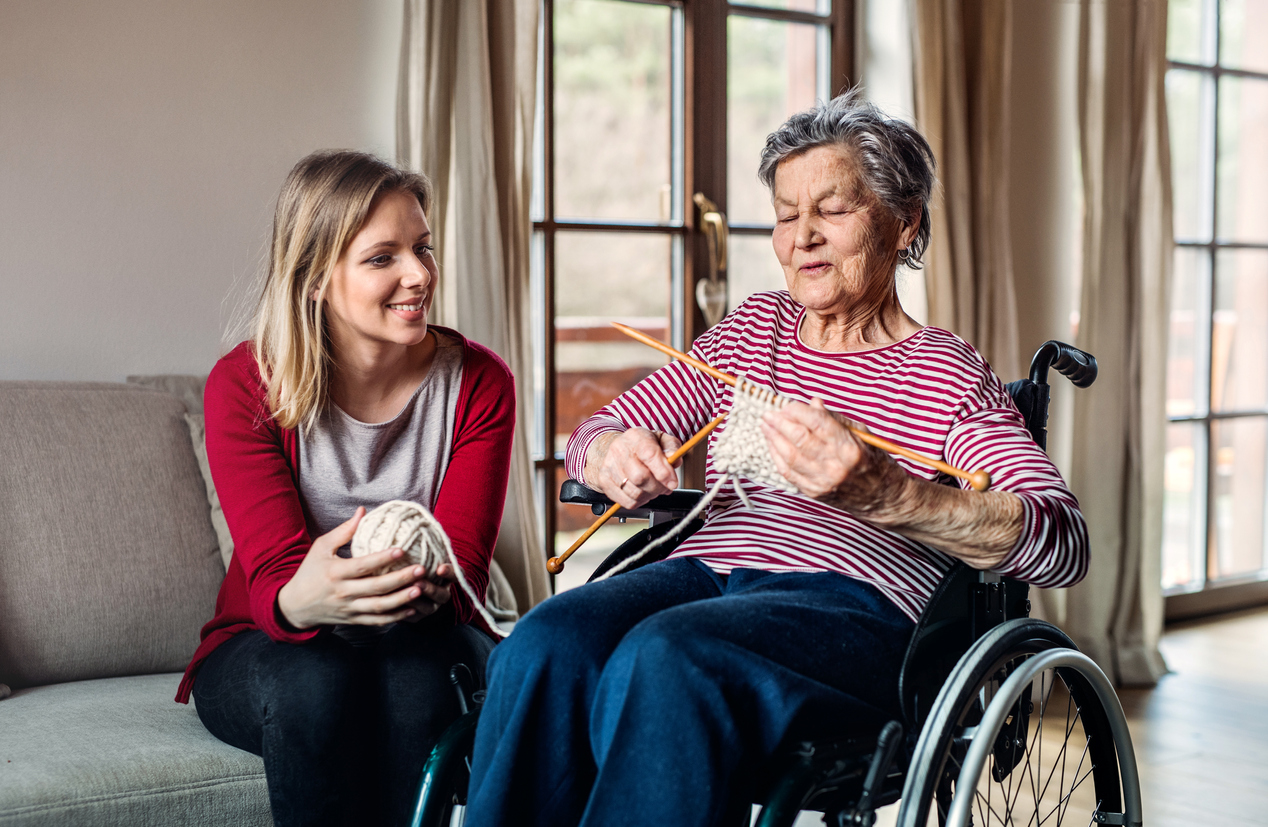 An elderly grandmother in wheelchair with an adult granddaughte