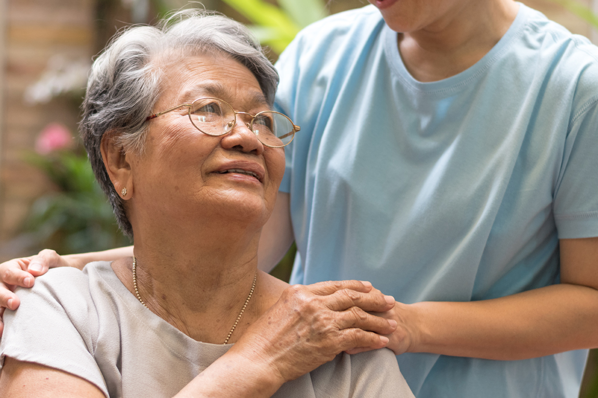 caregiver and senior woman holding hands