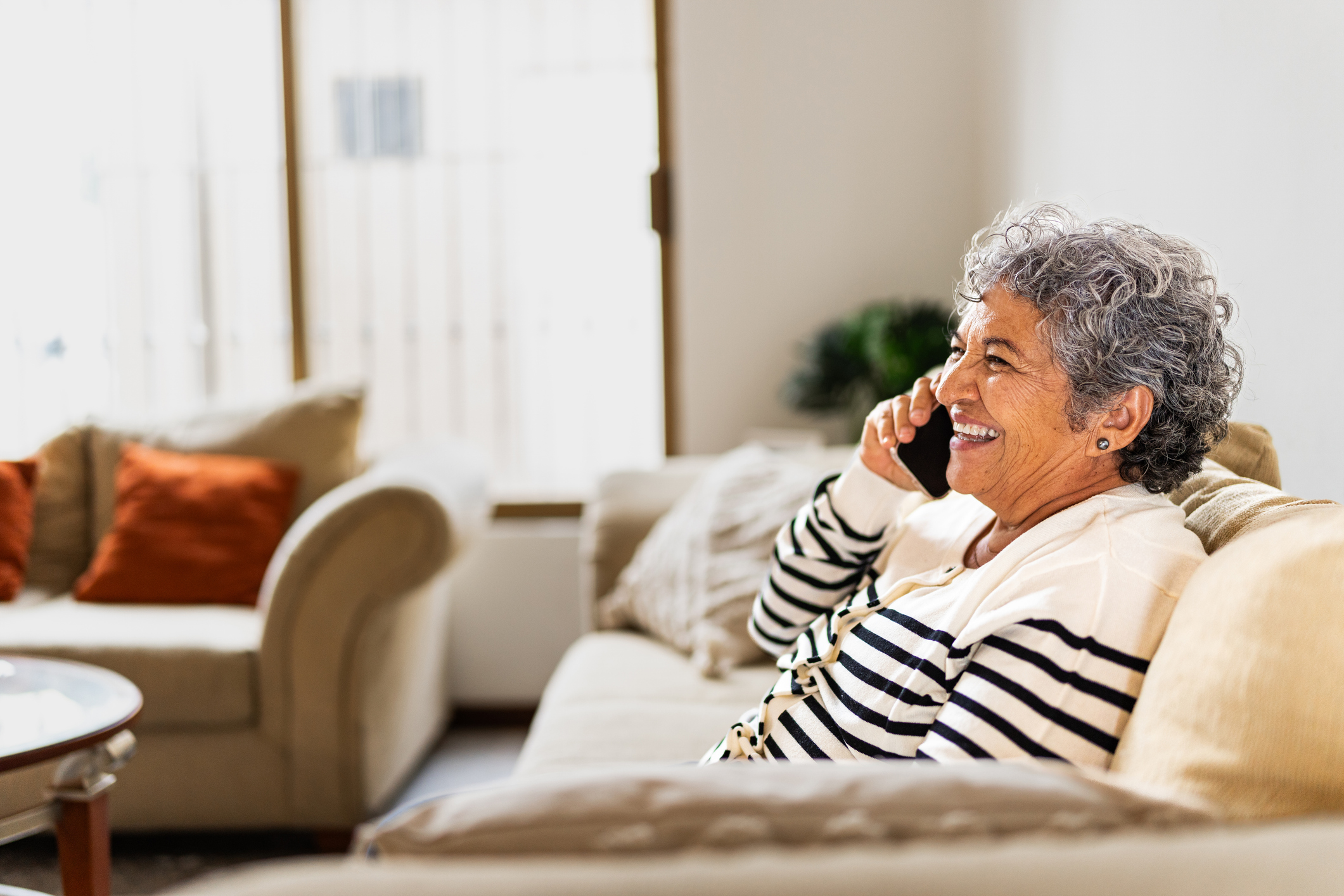 Senior woman smiling while talking on mobile phone at home