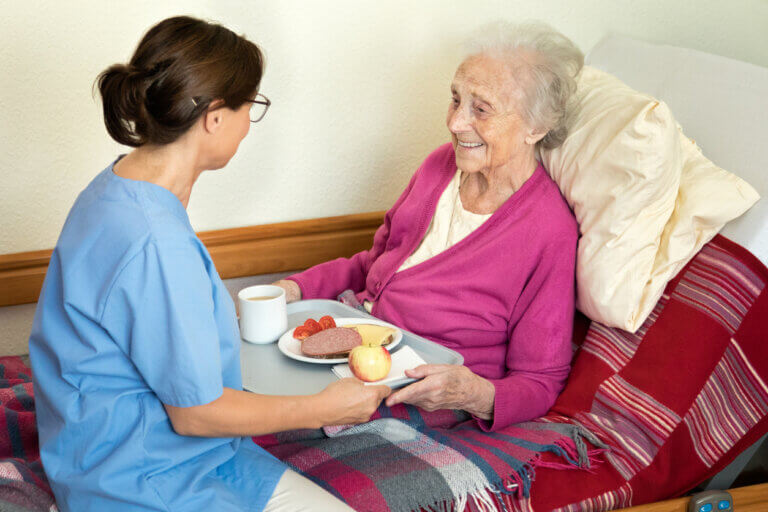 Home caregiver with senior adult woman, serving a meal