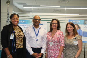 Erika Thomas, Phillip W. Heath, Donna Fahey, and Kaytie Brownstein in front of Samaritan Boccolini Institute's CAPC research presenation