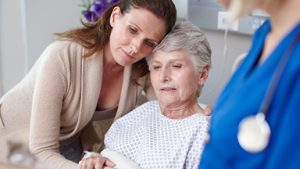 adult daughter embracing mom in hospital gown