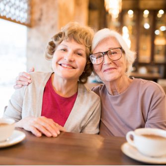 cheerful senior lady friends in coffee shop