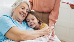 Woman with daughter visiting her mother at hospital, she is talking with doctor and showing love and care for her mother.