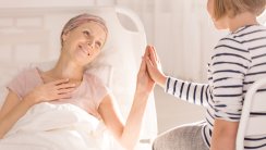 Cancer woman lying in hospital bed, touching child's hand