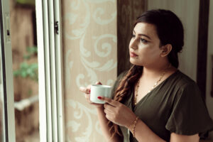  Woman looking out a window drinking from a mug