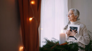 Elderly women clutching a book looking out window