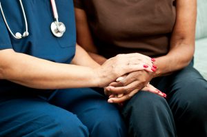 Healthcare worker holding the hands of a patient