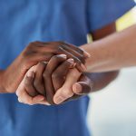 medical practitioner holding a patient's hand in comfort