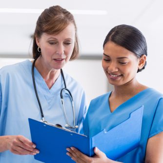 nurse and doctor discussing over clipboard