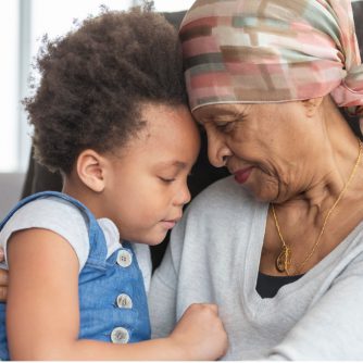 senior woman with cancer lovingly holds granddaughter